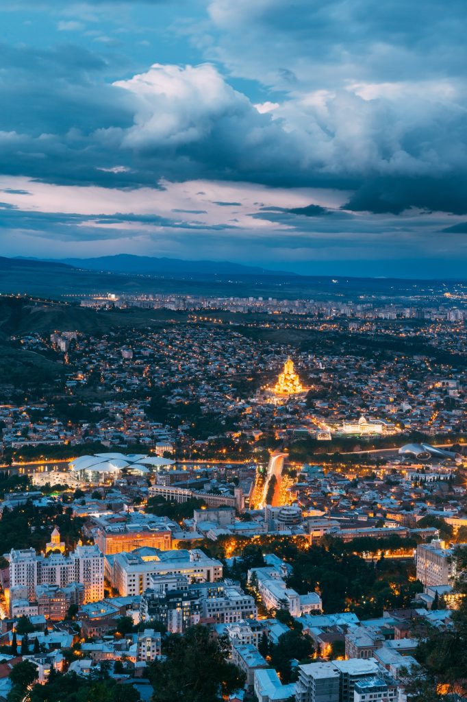 Tbilisi Georgia. Aerial Scenic Cityscape View In Evening Illimin